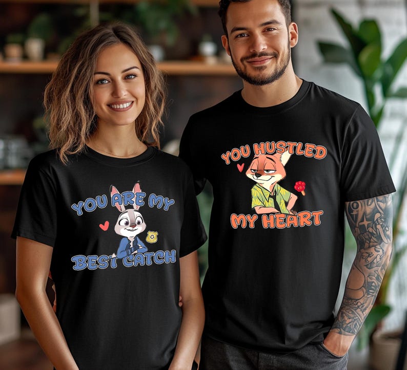 May include: Two black t-shirts featuring cartoon characters. The left shirt displays a rabbit with a badge and the text "YOU ARE MY BEST CATCH". The right shirt displays a fox holding a red popsicle with the text "YOU HUSTLED MY HEART".