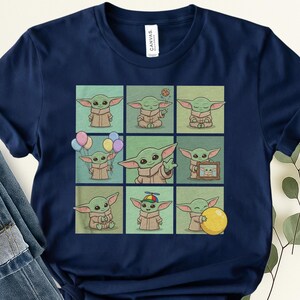 May include: Navy blue t-shirt with a grid of nine illustrations of a green alien character. Each square shows the character in different poses, holding a cookie, balloons, and a yellow ball. The shirt has a classic crew neck.