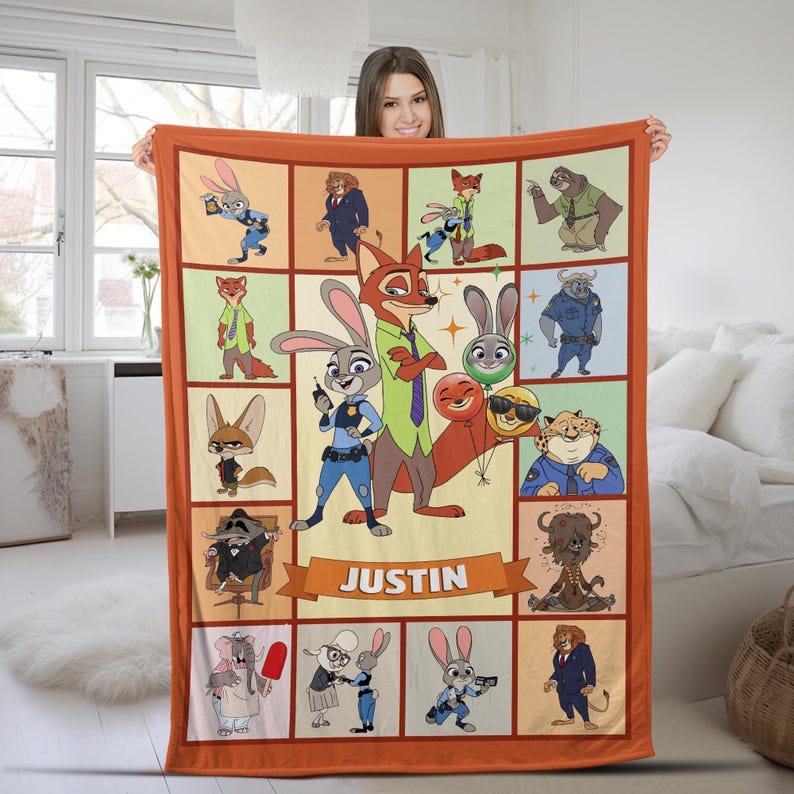 May include: A rectangular orange blanket featuring a grid of cartoon characters from the movie Zootopia. The blanket has a personalized banner that reads "JUSTIN". The characters include a fox, a bunny, a sloth, and a cheetah.