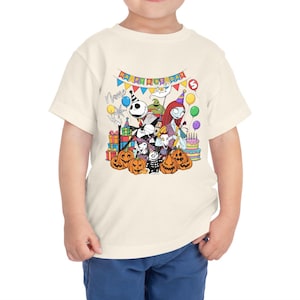 May include: A cream-colored toddler t-shirt featuring a colorful graphic of characters from The Nightmare Before Christmas. The design includes Jack Skellington, Sally, and pumpkins, with the text "Happy Birthday" and a number 5.