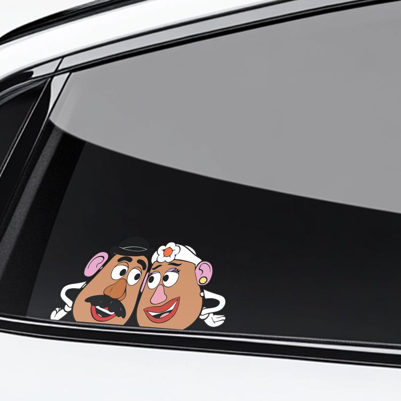 May include: A car window decal featuring a cartoon couple with potato-shaped heads. The male character has a black mustache and hat, while the female character wears a white headpiece. Both have pink ears and are smiling.