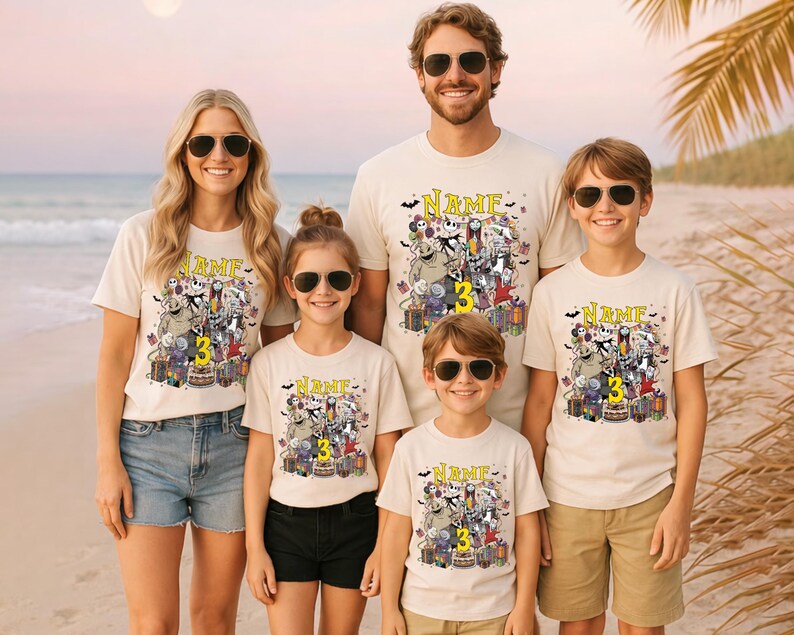 Pode incluir: Uma fam&iacute;lia de cinco pessoas vestindo camisetas creme combinando com um design gr&aacute;fico colorido com personagens, um bolo e o n&uacute;mero 3. As camisas t&ecirc;m a palavra "NAME" impressa acima do gr&aacute;fico.