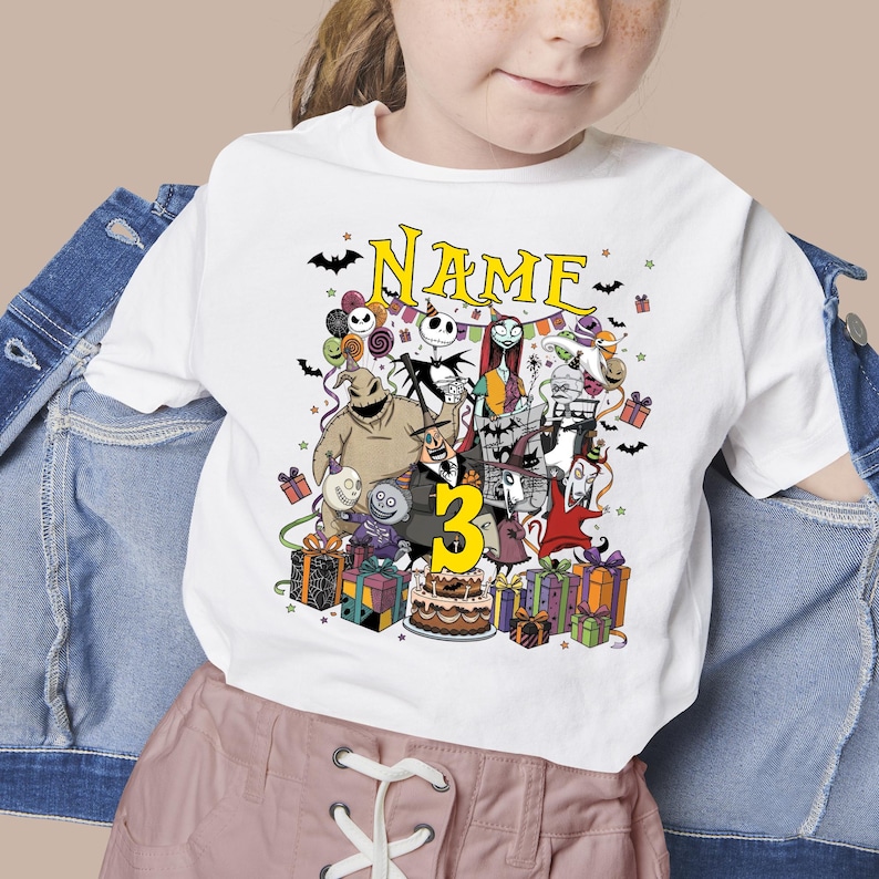 May include: White t-shirt featuring a colorful graphic of characters from The Nightmare Before Christmas, with the number 3 and the word "Name" in yellow. The design includes presents, bats, and a birthday cake.