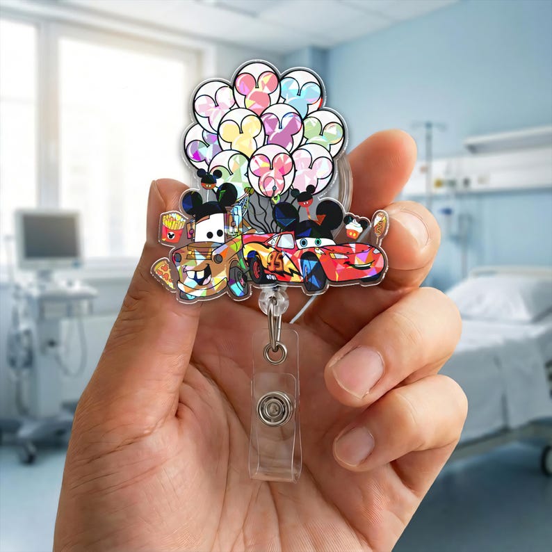 Op de afbeelding: Een kleurrijke badgehouder met cartoonauto's en Mickey Mouse-vormige ballonnen. De houder bevat afbeeldingen van Mater en Bliksem McQueen, met een doorzichtige plastic clip en een intrekbaar koord.