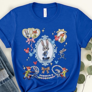 May include: A royal blue t-shirt featuring a colorful graphic design from the movie Zootopia. The design includes images of Judy Hopps and Nick Wilde, along with the text "Welcome to Zootopia". The shirt has short sleeves and a crew neck.