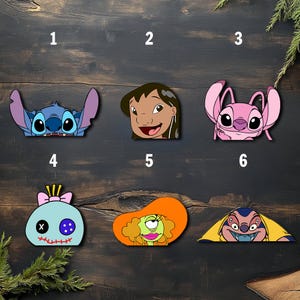 May include: A collection of six colorful character cutouts from the animated film Lilo & Stitch. The cutouts feature Stitch, Lilo, Angel, Scrump, Gantu, and another character. Each cutout is a different shape and color, with a cartoonish design.