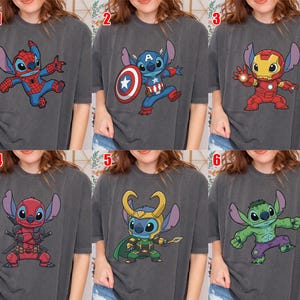 May include: Six dark gray t-shirts featuring cartoon character Stitch in various superhero costumes: Spider-Man, Captain America, Iron Man, Deadpool, Loki, and Hulk. Each design is colorful and detailed.