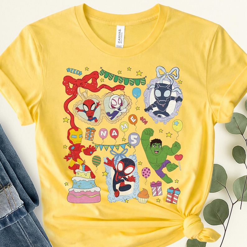 May include: A bright yellow short-sleeved t-shirt featuring a colorful graphic print of various superheroes, including Iron Man, Hulk, and Spider-Man characters. The design includes party elements like balloons, gifts, a cake, and the text NAME 5.