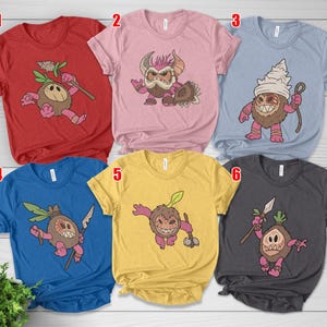 Puede incluir: Una colecci&oacute;n de seis camisetas de manga corta en varios colores, cada una con un dise&ntilde;o de personaje de dibujos animados &uacute;nico. Los dise&ntilde;os incluyen una criatura parecida a un coco con varios accesorios y expresiones. Las camisetas son rojas, rosas, azul claro, azules, amarillas y carb&oacute;n.