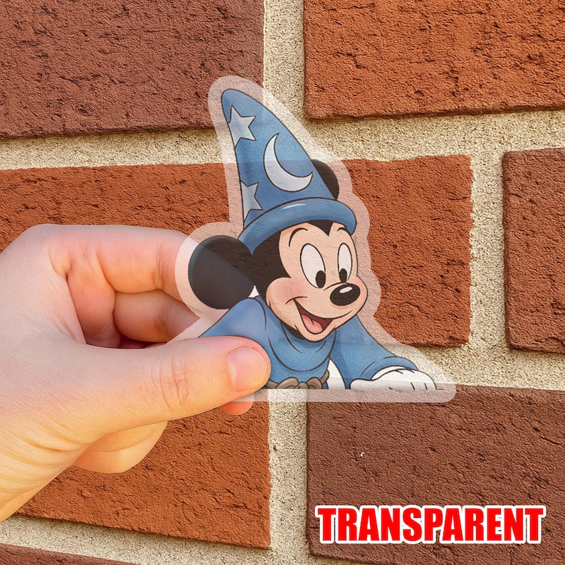 Puede incluir: Una pegatina transparente con Mickey Mouse vestido con un atuendo de mago azul, con una luna y estrellas en su sombrero. La pegatina tiene la palabra "TRANSPARENT" en letras rojas.