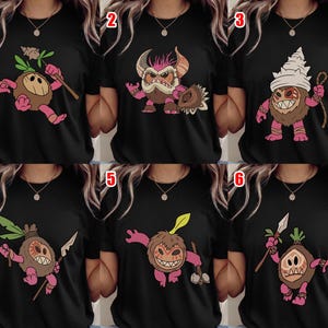 Puede incluir: Camisetas negras con varios dise&ntilde;os de monstruos de dibujos animados. Cada camiseta presenta una ilustraci&oacute;n de monstruo diferente en marr&oacute;n, rosa y blanco, sosteniendo armas o herramientas. Los dise&ntilde;os incluyen una criatura parecida a un coco y un monstruo con cuernos.