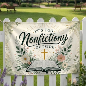 May include: A banner with the text "IT'S TOO Nonfictiony OUTSIDE" in dark green script, surrounded by floral and leaf illustrations. A gold cross and an open book are also featured. The banner is hanging on a white picket fence.