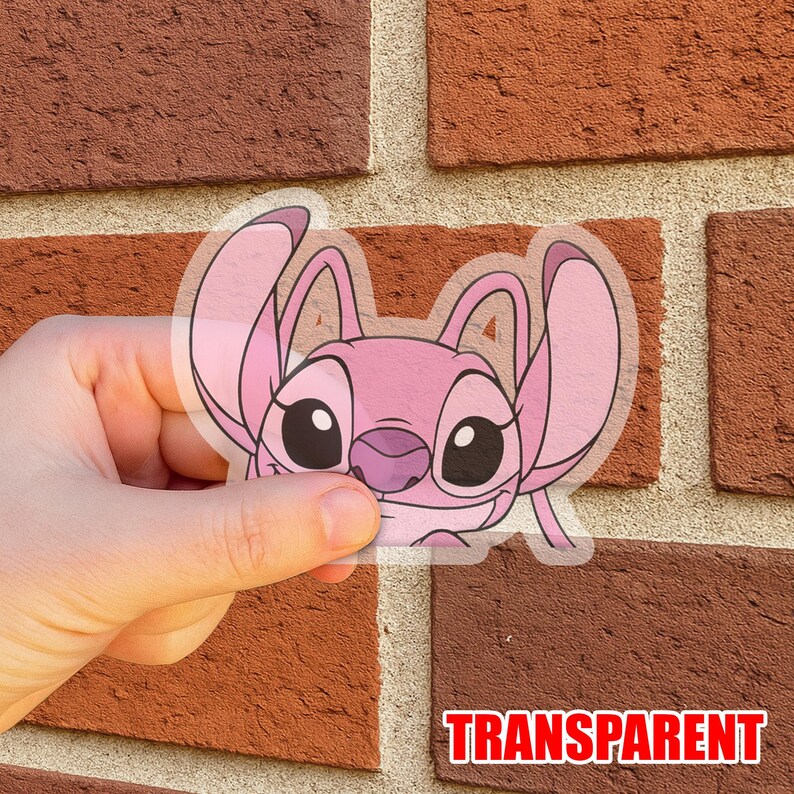 May include: A transparent sticker featuring a pink cartoon character with large eyes and ears. The sticker has the word "TRANSPARENT" in a red font at the bottom. The sticker is held in front of a brick wall.
