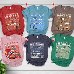 May include: A collection of six short-sleeved t-shirts featuring graphics from the animated movie "Cars." The shirts are in various colors, including red, blue, brown, pink, navy, and green, each with a different character design.