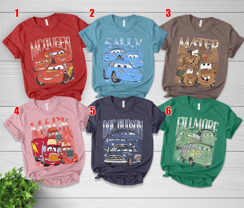 May include: A collection of six short-sleeved t-shirts featuring graphics from the animated movie "Cars." The shirts are in various colors, including red, blue, brown, pink, navy, and green, each with a different character design.