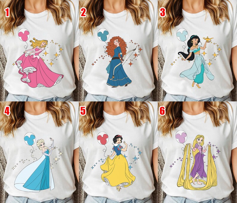 May include: White t-shirts featuring various cartoon princess designs. Each shirt showcases a different princess with a balloon and sparkling accents. The princesses include Aurora, Merida, Jasmine, Elsa, Snow White, and Rapunzel.