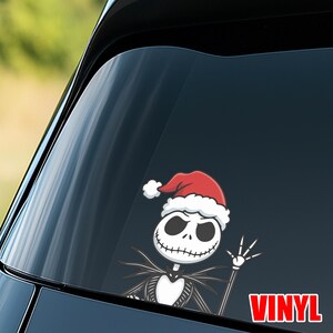 Op de afbeelding: Een vinyl sticker met Jack Skellington uit The Nightmare Before Christmas met een kerstmuts. Het zwart-witte personage zwaait, met het woord "VINYL" in rode blokletters.
