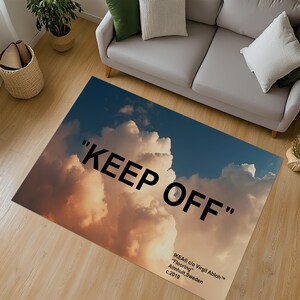 Può includere: Un tappeto bianco con uno sfondo di cielo blu e nuvole bianche. Il testo "KEEP OFF" è stampato in nero sul tappeto. Il testo "IKEA® c/o Virgil Abloh™" è stampato in nero nella parte inferiore del tappeto.