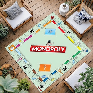 May include: A large Monopoly game board rug with a light green background and colorful property spaces. The Monopoly logo is prominently displayed in red and white. The board is surrounded by wooden chairs and outdoor plants.