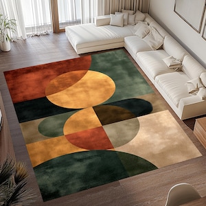 Op de afbeelding: Een groot vloerkleed met een abstract geometrisch ontwerp. Het vloerkleed heeft een combinatie van kleuren, waaronder roest, goud, groen en beige. Het ontwerp bevat grote cirkels en rechthoekige vormen, wat een moderne esthetiek creëert.