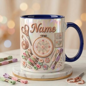 May include: A white iridescent ceramic mug with a dark blue interior and handle, featuring the word Name in script, an embroidery hoop, scissors, a measuring tape, needles, and colorful embroidery floss skeins printed on the exterior surface.