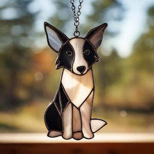 Könnte beinhalten: Glasmalerei-Hundefigur, die einen Border Collie im Sitzen darstellt, mit einem schwarz-weißen Design. Die Figur hängt an einer Metallkette. Die Ohren sind durchscheinend, der Körper besteht aus schwarzem, weißem und cremefarbenem Glas.