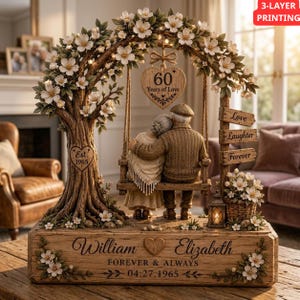 Op de afbeelding: Een decoratief beeldje van een ouder echtpaar op een schommel onder een bloeiende boom. De voet is gegraveerd met "William", "Elizabeth", "Forever & Always" en "04.27.1965". Een hartvormig bordje toont de tekst "60 Years of Love".