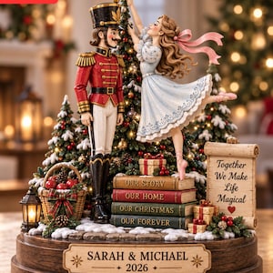 Puede incluir: Una figura decorativa que muestra a un cascanueces con uniforme rojo y a una bailarina con vestido azul claro colocando una estrella en un árbol de Navidad. La base muestra el texto SARAH & MICHAEL 2026 y un pergamino dice Together We Make Life Magical.