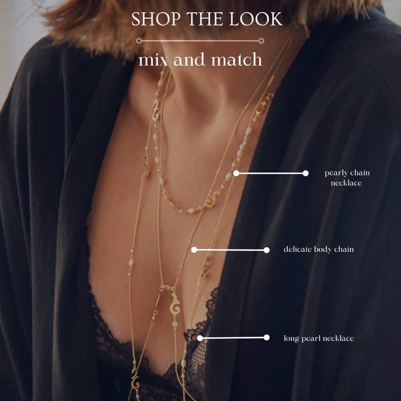 Puede incluir: Una mujer lleva una blusa negra con un collar de cadena dorada en capas, una cadena de cuerpo delicada y un collar largo de perlas. El texto "SHOP THE LOOK" y "mix and match" se muestra encima de la imagen.