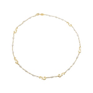 Puede incluir: Un collar de oro con peque&ntilde;as perlas blancas y dijes de oro en forma de espirales.