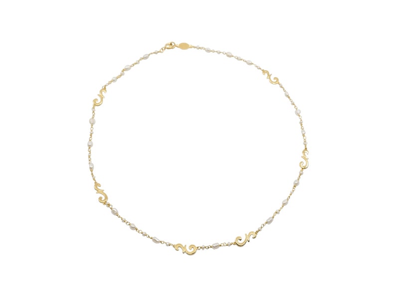 Puede incluir: Un collar de oro con peque&ntilde;as perlas blancas y dijes de oro en forma de espirales.