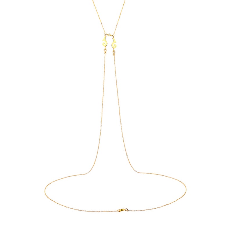 Puede incluir: Un collar de cadena de oro con dos dijes decorativos en la parte superior y un cierre de langosta.