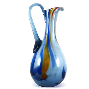 May include: A blue glass pitcher with a swirl design in shades of blue, yellow, and white. The pitcher has a curved handle.
