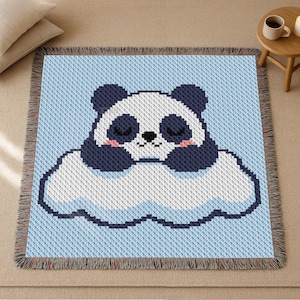 May include: A blue throw blanket with a woven panda bear design. The panda has a white face, black ears and eyes, and is resting on a white cloud. The blanket has a blue background and a fringed border.