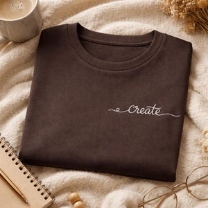 Op de afbeelding: Een witte keramische mok met een zwart handvat en de tekst "But First, Coffee" in een zwarte, vette letter. De mok staat op een wit oppervlak.