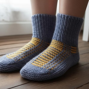 May include: A pair of blue knitted socks with yellow striped detailing on the foot and ankle. The socks are shown on a wooden floor, highlighting the handmade quality and cosy design. These socks are a comfortable and warm accessory.
