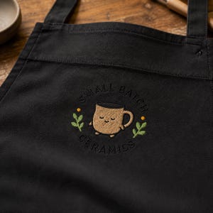 Organic Cotton Pottery Apron With Embroidered Ceramic Mascot Design Adjustable Canvas Workwear Smock For Clay Artists Painters And Gifts