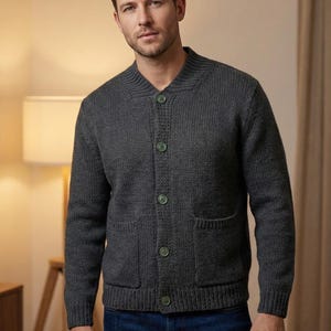 Puede incluir: Un cárdigan gris carbón con cierre de botones, dos bolsillos delanteros y puños acanalados. El suéter tiene un diseño clásico con cuello redondo y botones verdes. El modelo lleva vaqueros azules.