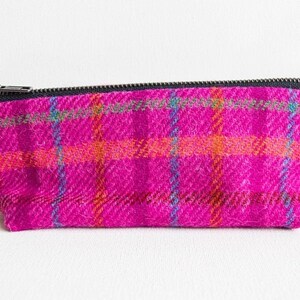 May include: A pink and orange plaid zippered pouch with a black zipper.
