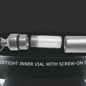 May include: A silver, airtight vial with a screw-on cap. The vial is separated into three parts: a cap, a clear glass tube, and a base with a ring for attaching a keychain.