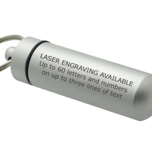 Pode incluir: Um porta-chaves cil&iacute;ndrico de metal prateado com tampa de rosca e argola de metal. A lateral do recipiente apresenta um texto impresso a preto que diz: LASER ENGRAVING AVAILABLE Up to 60 letters and numbers on up to three lines of text.