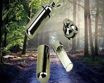 May include: A collection of silver-colored, cylindrical vials and a keychain pendant. The vials have a polished, reflective surface. One vial is open, revealing a clear interior. The background is a blurred forest scene with a path.