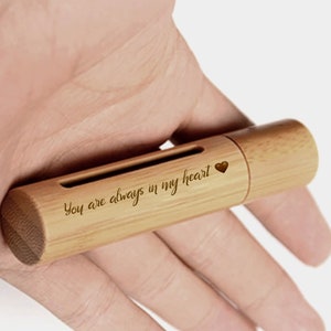 May include: A light brown, cylindrical bamboo USB flash drive. The text "You are always in my heart" is engraved on the side, along with a small heart symbol. The drive has a slot and a cap.