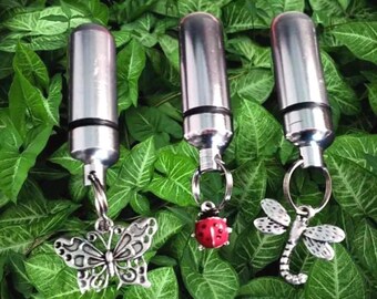 May include: Three silver-colored keychain flashlights with decorative charms. One charm is a butterfly, another is a ladybug, and the third is a dragonfly. The flashlights are cylindrical and have a black band near the top.