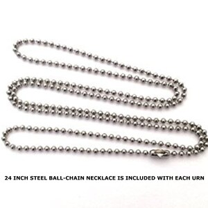 May include: A steel ball-chain necklace, approximately 24 inches long, is displayed against a white background. The necklace is composed of small, evenly spaced metal balls and features a clasp at one end. The text at the bottom reads: "24 inch steel ball-chain necklace is included with each urn."