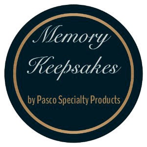 May include: A circular logo with a navy blue background and a gold border. The words "Memory Keepsakes" are written in elegant script, with "by Pasco Specialty Products" below in a smaller font.