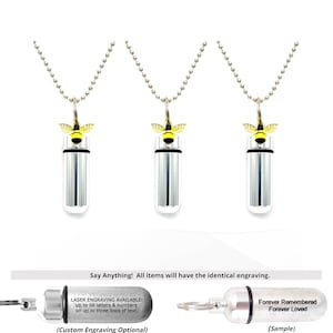 May include: Three silver-colored, cylindrical pendant necklaces with a bee charm. The bee charm is yellow and black. The necklaces have a ball chain. The text in the image says, "Say Anything! All items will have the identical engraving."
