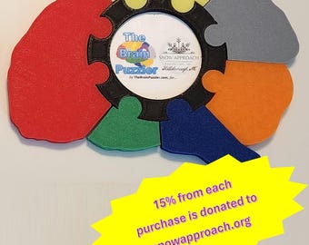 May include: A colorful brain-shaped puzzle with a black frame and the text "The Brain Puzzler" inside. The puzzle is made of foam and has a variety of colors, including red, orange, yellow, green, blue, and gray. 15% of each purchase is donated to snowapproach.org.