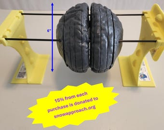 May include: A dark gray, segmented anatomical brain model suspended between two yellow plastic stands by thin metal rods. A blue arrow indicates a height of 6 inches. A yellow starburst graphic displays the text: 15% from each purchase is donated to snowapproach.org.