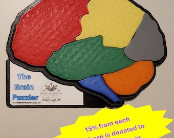 May include: A 3D printed brain puzzle with different colored sections. The puzzle is black outlined and has the text "The Brain Puzzler" and "SNOW APPROACH Foundation, Inc.  Middleborough, MA" on the bottom. The text "15% from each purchase is donated to snowapproach.org" is on a yellow starburst.